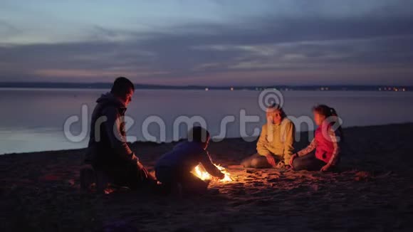 一家游客在夜间海滩的篝火旁休息视频的预览图