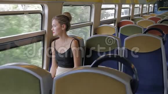一位美丽的白种人女游客独自坐在空舱地铁列车上望着窗外在她身后视频的预览图