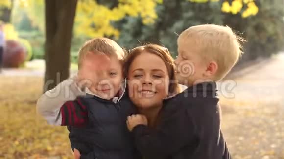 快乐的年轻母亲和小儿子在秋天公园肖像视频的预览图
