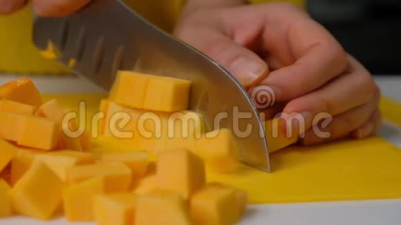 女厨师把南瓜切成小块南瓜在木板上煮南瓜奶油汤的原料视频的预览图