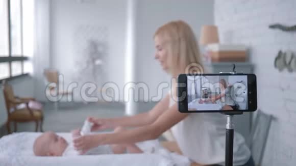 博客行业现代母亲vlogger在手机上录制培训视频时为小女孩做按摩视频的预览图