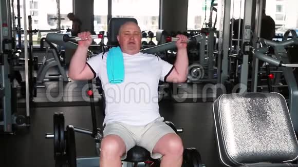 健身房里的男人在模拟器上做手臂和肩膀的运动视频的预览图