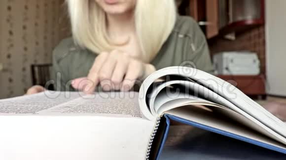 一个模糊的面目全非的金发女人在翻阅一本大书一根手指在书页上视频的预览图