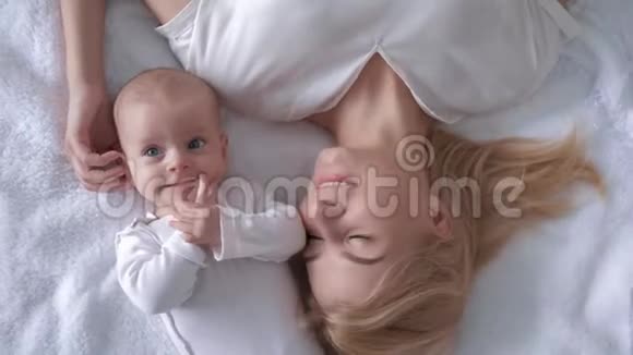 新的家庭在迷人的母亲和漂亮的新生儿躺在白色的床上近距离观看视频的预览图