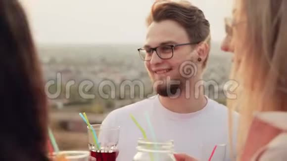 一个长着胡子戴着眼镜和他的朋友们站在屋顶上喝着美味的东西的白种人视频的预览图