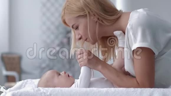 快乐的妈妈抚摸并亲吻她可爱的新出生的小女孩她躺在换桌子上紧紧地拥抱着她视频的预览图