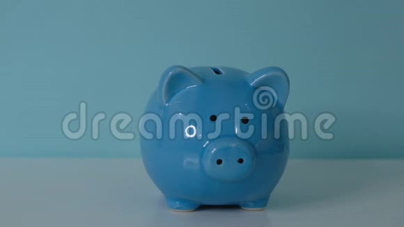猪银行的经营理念一只手把硬币放在蓝色背景上的储蓄罐里省钱就是视频的预览图
