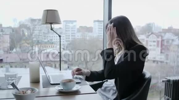 愤怒和严肃的反应年轻女子坐在木桌旁的咖啡店里桌子上有一台灰色铝制笔记本电脑视频的预览图