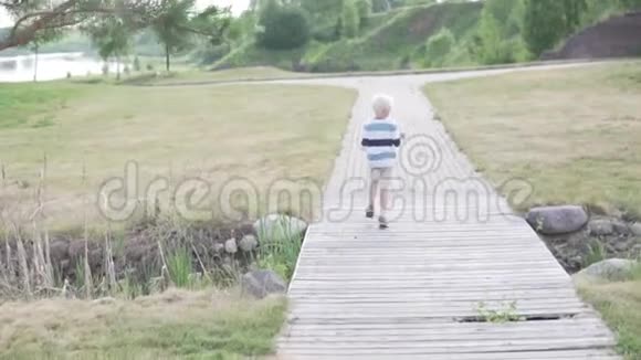 夏天英俊的金发男孩穿过公园视频的预览图