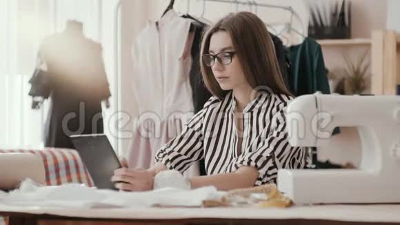 设计师女裁缝在笔记本电脑上读取文本并在织物上做标记视频的预览图