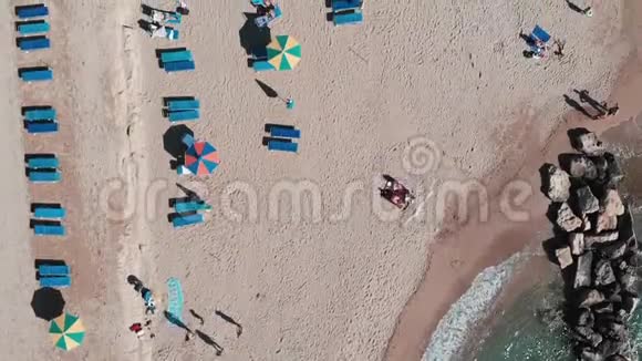 无人机用雨伞和日光浴床沿着海滩飞行沙滩的鸟瞰图海岸线上的美丽景色高空顶部v视频的预览图