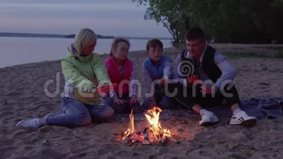 父亲母亲和孩子们在晚上因火灾而变暖在海上停了下来视频的预览图