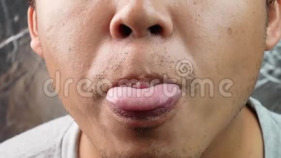 亚洲中年男子在灰色背景下迅速伸出舌头视频的预览图