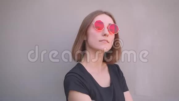 年轻的酷白种人女孩戴着红色时髦太阳镜肩上戴着皮夹克面带微笑的特写肖像视频的预览图