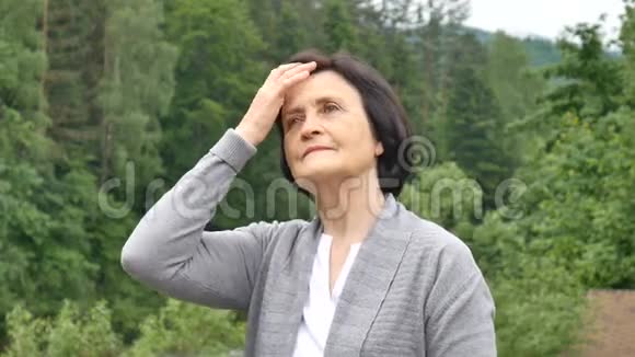 在山林背景下美丽的老妇人用手伸直头发养恤金领取者视频的预览图