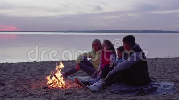 日落时分有孩子在篝火旁聊天的家人视频的预览图