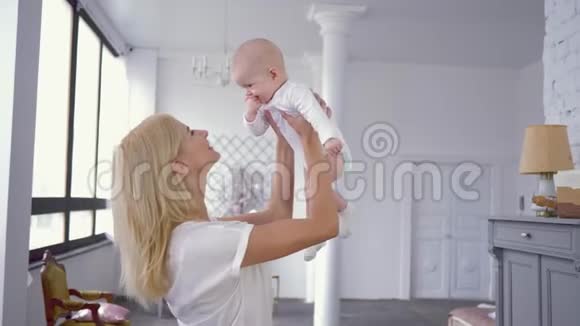 父母的爱快乐的年轻母亲在可爱的婴儿女孩的头顶上玩耍和养育她咬着手指视频的预览图