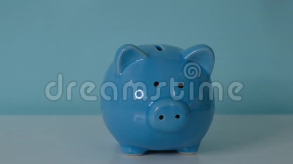 猪银行的经营理念一只手把硬币放在蓝色背景上的储蓄罐里省钱就是视频的预览图