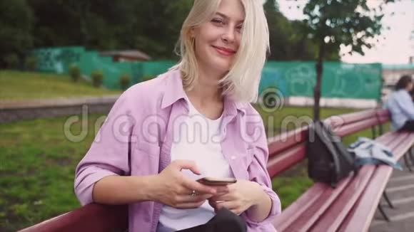 十几岁的女孩用智能手机坐在长凳上发短信视频的预览图