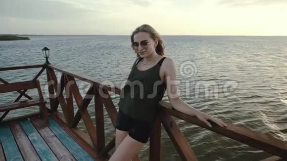 一个女孩在日落时在海上的一个木制码头的肖像视频的预览图