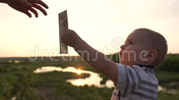 在日落时分一个小男孩慢吞吞地给一个成年人送钞票视频的预览图