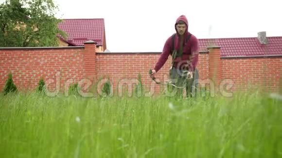 有人用汽油割草机割草摄像机在草地上拍摄视频的预览图