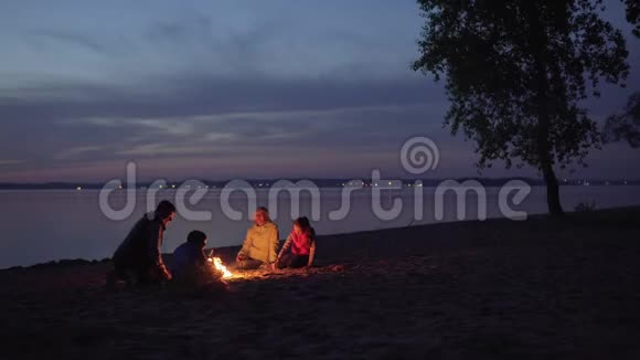 人们在海边徒步旅行时坐在火堆里视频的预览图