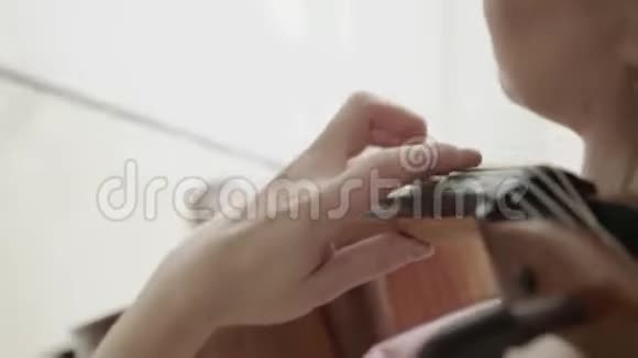 在灯光室的摄像机中由积极的女性小提琴手制作的乐器视频的预览图