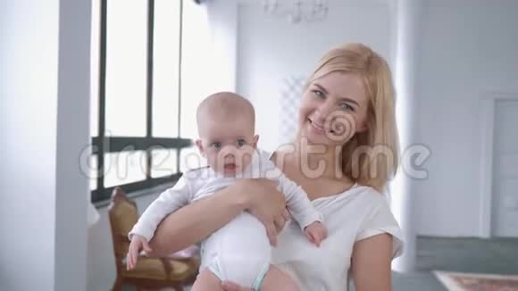 一幅家庭肖像可爱的妈妈把刚出生的女儿抱在怀里对着镜头微笑视频的预览图
