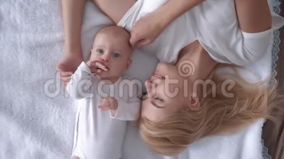 家庭休闲在美丽的母亲和一个美丽的新生婴儿躺在白色的床上近距离观看视频的预览图