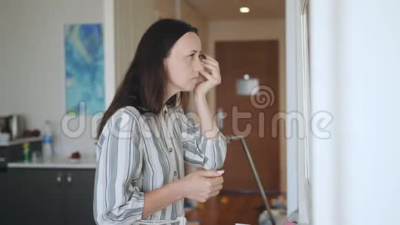 一个中年妇女在镜子前化妆离开房子前一百视频的预览图