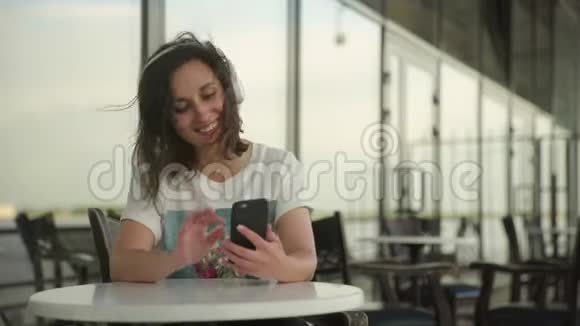 戴着耳机听音乐和在智能手机上聊天的年轻女性视频的预览图