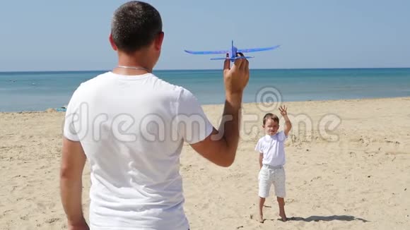 幸福家庭父子在海边玩耍爸爸向旁边发射一架玩具飞机站在孩子旁边这就是视频的预览图