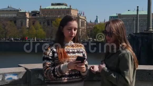 两个年轻的旅行妇女站在桥上看着锁屏视频的预览图