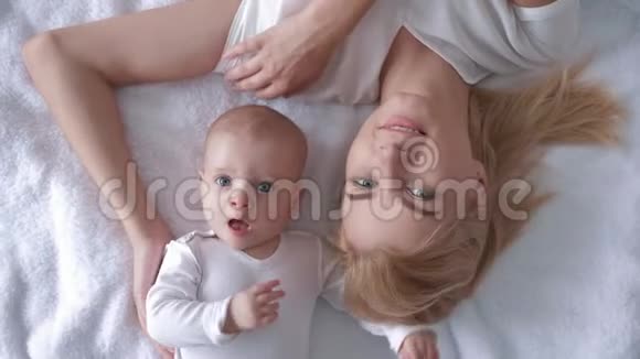 温柔的时刻幸福的父母和新生儿躺在床上俯视着小女孩抚摸着母亲的头发视频的预览图