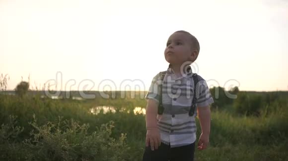 一个穿着时髦衬衫的可爱小男孩在户外慢动作击球视频的预览图