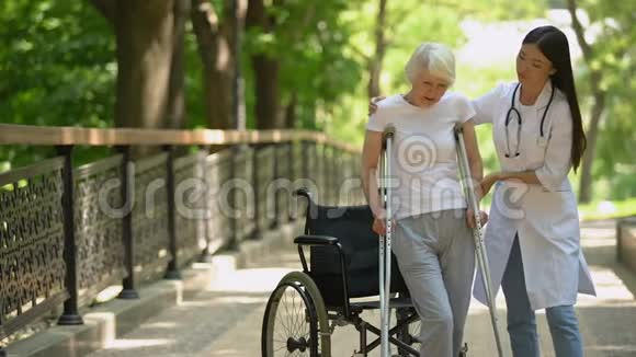 医生帮助残疾老年妇女拄着拐杖走路创伤后恢复视频的预览图