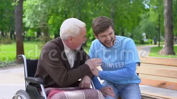 坐在轮椅上的老年男性和志愿者一起欢笑和开玩笑一起玩视频的预览图