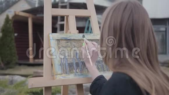 职业年轻女孩坐在后院户外画布上画画充满激情的成功艺术家视频的预览图