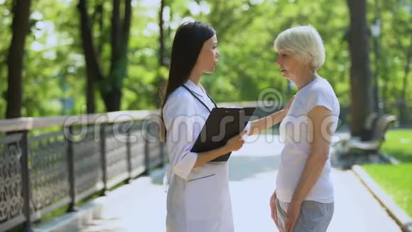 老年妇女向医院公园的年轻护士抱怨心痛医疗保健视频的预览图