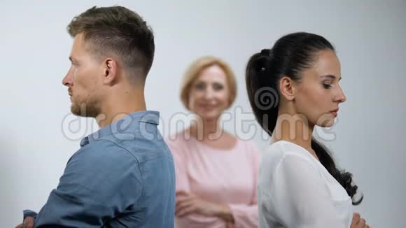 满意的母亲看着争吵中的一对夫妇站在彼此之间视频的预览图