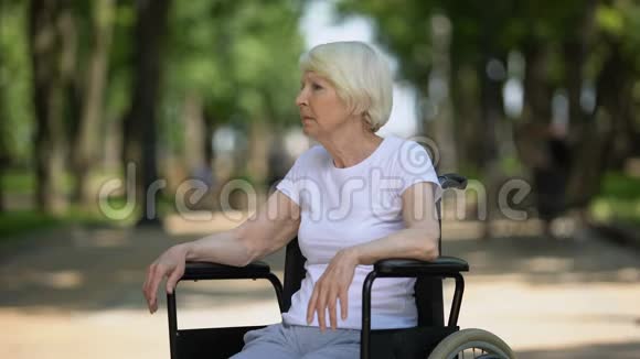 在康复中心公园坐轮椅的忧郁的老年女性视频的预览图