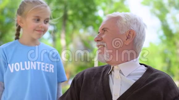 快乐的孩子志愿拥抱男性养老金领取者互相微笑老人关心视频的预览图