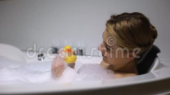 积极的女人在洗澡时玩橡皮鸭孩子气玩得开心视频的预览图