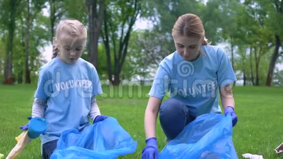 白人妇女带着女孩子在公园里收集垃圾互相微笑视频的预览图