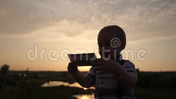 一个优雅的小男孩在日落时慢吞吞地亲吻一百美元的钞票视频的预览图