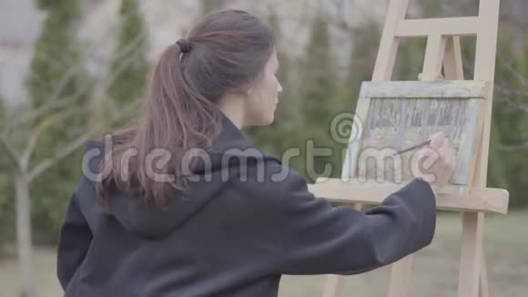 成功的艺术家在后院的画布上作画美丽热情的女孩从事创造力艺术学院视频的预览图