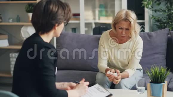 闷闷不乐的成熟女士在舒适的办公室与女心理学家讨论问题视频的预览图