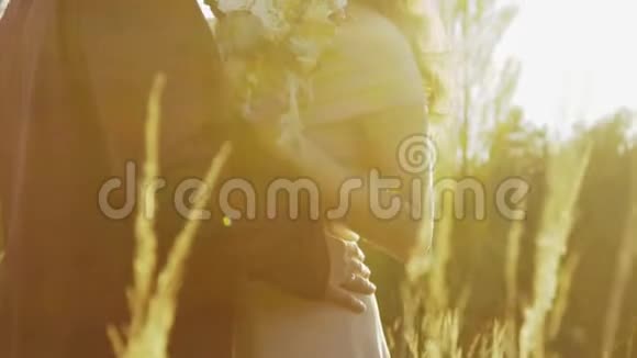 新婚夫妇在荒野的草原上在阳光的照耀下互相抚吻视频的预览图