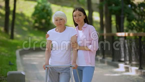 悲伤的老年患者步行架和女儿看相机社会不安全视频的预览图